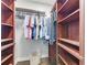 Spacious walk-in closet with custom dark wood shelves, hanging racks and hardwood flooring at 6674 Coopers Hawk Ct, Lakewood Ranch, FL 34202