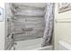 Tiled tub/shower featuring modern fixtures, grab bar, and shower caddy for storage at 6713 Midnight Pass Rd # 4, Sarasota, FL 34242