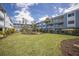 Beautiful building featuring manicured lawn, mature trees and plants, offering a serene outdoor experience at 7000 Gulf Dr # 205, Holmes Beach, FL 34217