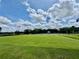 Spacious lawn with green grass and blue sky and clouds, perfect for outdoor activities at 7330 Kensington Ct, University Park, FL 34201