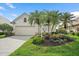 Single story home featuring lush landscaping with palm trees and colorful flower beds, with a two car garage at 7821 Troon Ct, Lakewood Ranch, FL 34202