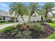 Charming single-story home featuring lush landscaping with palm trees and colorful flower beds adding curb appeal at 7821 Troon Ct, Lakewood Ranch, FL 34202