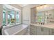 Bathroom with a soaking tub, dual sink vanity, and a view of the outdoors at 878 Freeling Dr, Sarasota, FL 34242