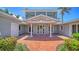 Inviting entryway features a brick pathway, covered porch with columns, and lush tropical landscaping at 878 Freeling Dr, Sarasota, FL 34242