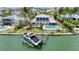 A waterfront property featuring a boat lift and a stunning two-story home surrounded by swaying palm trees at 878 Freeling Dr, Sarasota, FL 34242