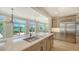 Bright, modern kitchen features large island with sink and stainless steel refrigerator, with water views at 878 Freeling Dr, Sarasota, FL 34242