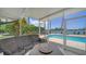 Relax in this screened-in patio with wicker furniture, a fire pit, and a view of the sparkling pool at 878 Freeling Dr, Sarasota, FL 34242
