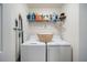 Functional laundry room with a washer, dryer, wire shelf, and a convenient folding basket at 910 Tidewater Shores Loop # 103, Bradenton, FL 34208