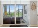 View of screened porch through glass doors with outdoor seating and tranquil views of green space at 910 Tidewater Shores Loop # 103, Bradenton, FL 34208