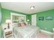 Bright bedroom featuring green walls, a patterned quilt, and white trim, creating a cozy and inviting atmosphere at 102 & 104 48Th St, Holmes Beach, FL 34217