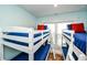 Bright bedroom showcases four bunk beds with matching blue bedding and red pillows at 102 & 104 48Th St, Holmes Beach, FL 34217