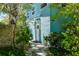 Inviting turquoise home featuring a white door, decorative awning, and lush tropical landscaping at 102 & 104 48Th St, Holmes Beach, FL 34217