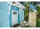 Charming turquoise home featuring a white door, decorative awning, and lush tropical landscaping at 102 & 104 48Th St, Holmes Beach, FL 34217