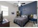 Bedroom showcasing blue accent wall, gray bedding, a ceiling fan, and decorative items on shelves at 11513 11Th E Ave, Bradenton, FL 34212