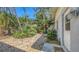 Charming side yard with mature trees, landscaping, and a stone pathway leading to the entrance at 120 Hammock Rd, Anna Maria, FL 34216