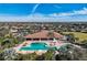 Aerial view of community pool, clubhouse, and palm trees with houses in the background on a sunny day at 12822 Del Corso Loop, Bradenton, FL 34211