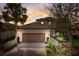 Charming two-story home with a brick driveway, lush landscaping, and warm exterior lighting at dusk at 12822 Del Corso Loop, Bradenton, FL 34211