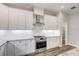 Modern island kitchen featuring white cabinets, granite countertops, stainless steel range hood, and hardwood flooring at 12822 Del Corso Loop, Bradenton, FL 34211