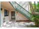 Front exterior view of condo entrance with a green staircase surrounded by tropical plants at 1629 Pelican Cove Rd # 138A, Sarasota, FL 34231