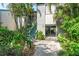 Multi-level condo with lush landscaping, a wooden staircase, and a pathway to the entrance at 1629 Pelican Cove Rd # 138A, Sarasota, FL 34231