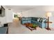 Bright living room with blue L-shaped sofa, wood coffee table, and view of outdoor patio at 1629 Pelican Cove Rd # 138A, Sarasota, FL 34231