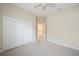A carpeted bedroom with ceiling fan and closet leads to another room; note the neutral wall color at 1739 Lake Verona Cir, Bradenton, FL 34211