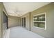 This is a covered patio with white flooring, a ceiling fan, and a sliding glass door to the interior at 1739 Lake Verona Cir, Bradenton, FL 34211