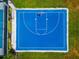 Aerial view of a blue basketball court surrounded by green grass and landscaping at 17904 Palmiste Dr, Bradenton, FL 34202