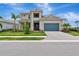 Stunning two-story home with a blue garage door, a manicured lawn, and tropical landscaping at 17904 Palmiste Dr, Bradenton, FL 34202