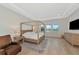 Bright main bedroom featuring a four-poster bed, light wood floors, and tray ceiling at 17904 Palmiste Dr, Bradenton, FL 34202