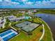 Aerial view of community tennis courts next to a pond with fountain and clubhouse with pool at 17904 Palmiste Dr, Bradenton, FL 34202