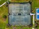 Aerial view of fenced tennis courts surrounded by green grass and manicured landscaping at 17904 Palmiste Dr, Bradenton, FL 34202