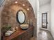 Arched bathroom with stone walls, wood vanity, vessel sink, large mirror, and doorway to the outdoor space at 3576 San Remo Ter, Sarasota, FL 34239