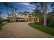 Elegant two-story home with a brick driveway, lush tropical landscaping, and a porte-cochere with a two car garage at 3576 San Remo Ter, Sarasota, FL 34239
