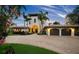 Elegant two-story home with a brick driveway, lush tropical landscaping, and a porte-cochere with a two car garage at 3576 San Remo Ter, Sarasota, FL 34239