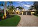 Elegant two-story home with a brick driveway, lush tropical landscaping, and a porte-cochere with a two car garage at 3576 San Remo Ter, Sarasota, FL 34239