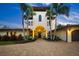Elegant two-story home with a brick driveway, lush tropical landscaping, and a porte-cochere with a two car garage at 3576 San Remo Ter, Sarasota, FL 34239