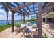 Outdoor seating area with a pergola overlooking the waterfront pool and backyard with palm trees at 3576 San Remo Ter, Sarasota, FL 34239