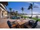 Outdoor dining table and chairs on the pool deck with views of the water and mature palm trees at 3576 San Remo Ter, Sarasota, FL 34239