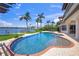 Backyard view of the kidney-shaped pool, intercoastal waterway, and dock with palm trees and an outdoor dining area at 3576 San Remo Ter, Sarasota, FL 34239