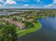 An aerial view of community buildings nestled near a tranquil lake with lush trees and landscaping at 4037 Crockers Lake Blvd # 17, Sarasota, FL 34238