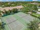 Aerial view of community tennis courts with surrounding mature trees, manicured lawn and nearby buildings at 4037 Crockers Lake Blvd # 17, Sarasota, FL 34238