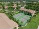 Aerial view of community tennis courts amid mature landscaping, grassy areas, and nearby apartment buildings at 4037 Crockers Lake Blvd # 17, Sarasota, FL 34238