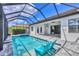 A screened-in pool with waterfall, jacuzzi and chairs is framed by a blue sky and tropical landscaping at 4312 Vasco St, Punta Gorda, FL 33950
