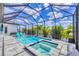 Screened pool area featuring a spa, pool, two lounge chairs, and beautiful landscaping with palm trees and blue skies at 4312 Vasco St, Punta Gorda, FL 33950
