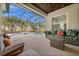 Covered patio with comfortable wicker furniture overlooking a screened-in pool and a beautiful yard with palm trees at 4542 Cedar Brush Ter, Sarasota, FL 34243