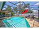 Relaxing in-ground pool with screened enclosure, lounge chairs and red umbrella at 5126 15Th W Ave, Bradenton, FL 34209