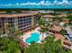 Aerial shot of pool area with palm trees, lounge chairs, building, and mature landscaping at 5561 Cannes Cir # 5101, Sarasota, FL 34231