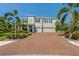 Charming two-story home with a three-car garage, brick driveway, lush landscaping, and beautiful palm trees at 5805 49Th E Ct, Ellenton, FL 34222