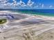 Expansive beach view featuring pristine white sand, emerald water, and rows of beach umbrellas under a partly cloudy blue sky at 5858 Midnight Pass Rd # 27, Sarasota, FL 34242